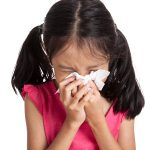 Little asian girl sneeze with napkin paper isolated on white background